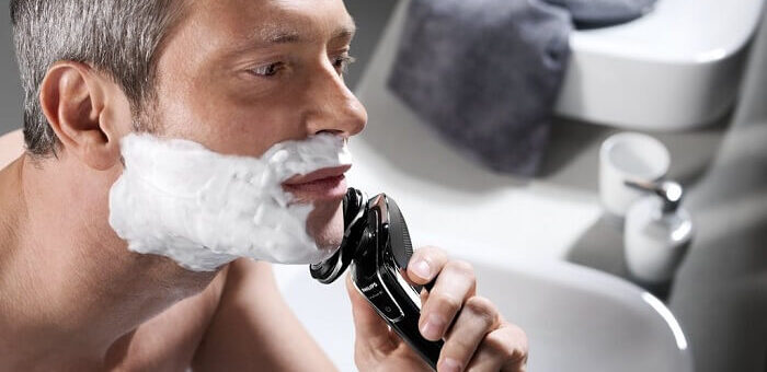 man uses Philips Norelco SensoTouch 3D/1250x shaver in bathroom