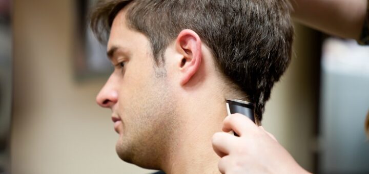 a barber cutting a man's hair with a hair clipper