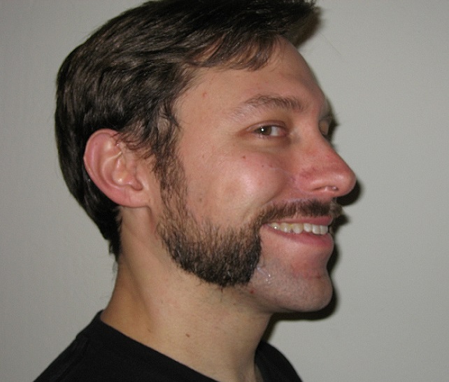 a smiling man with a mutton chops mustache