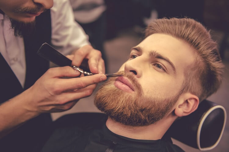 a young attractive man having his beard trimmed