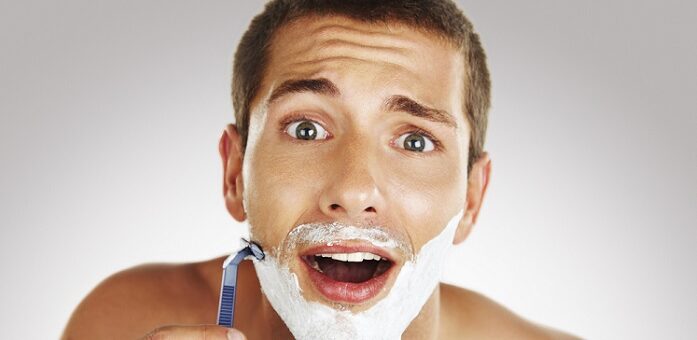 a young man looking surprised while shaving