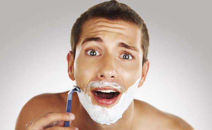 a young man looking surprised while shaving