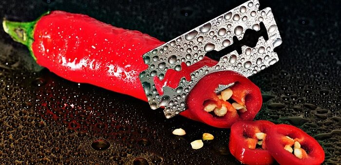 a razor blade cutting through a red pepper