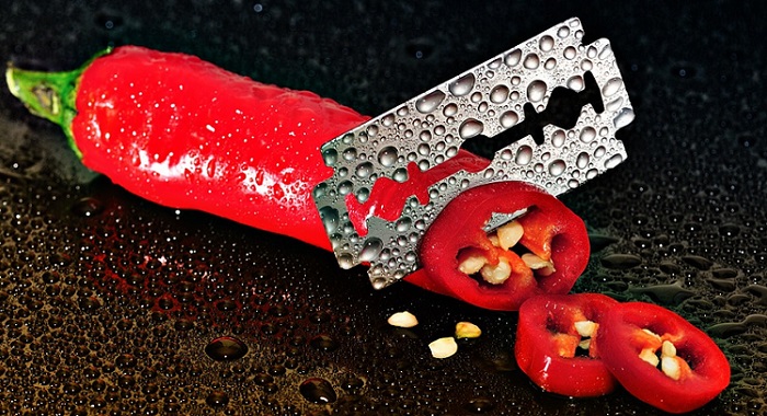 a razor blade cutting through a red pepper