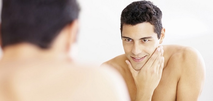 the reflection of a young man looking in the mirror with a freshly-shaved face