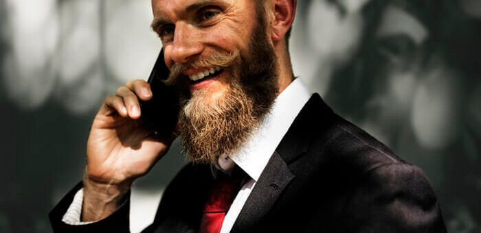 elegant business man smiling with long beard talking at the phone