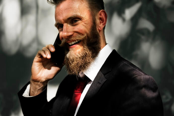 elegant business man smiling with long beard talking at the phone