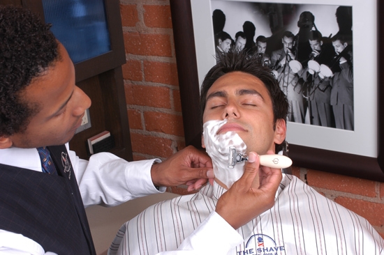 barber shaving a man with a straight razor