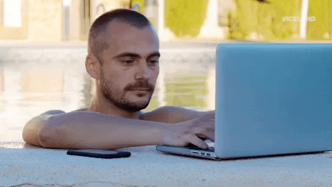 man using his laptop while being soaked in the swimming pool