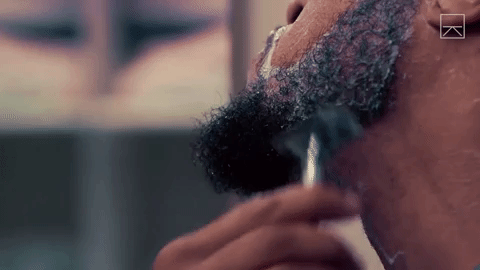 man is using a razor blade to shave off his beard
